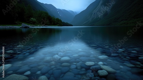 Obraz na płótnie Serene mountain lake at twilight. Clear water reflects the surrounding peaks and forests in a tranquil, peaceful scene. The shallows reveal a path of smooth stones w salonie
