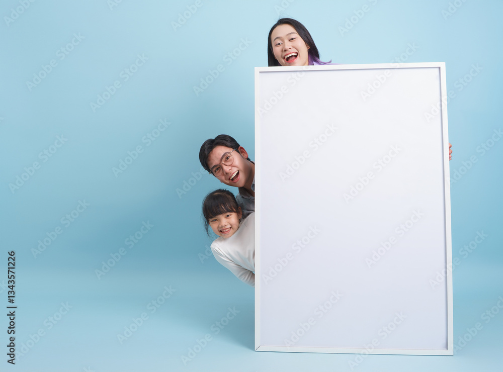 Family poses playfully behind a blank canvas in a vibrant studio with a light blue background Family poses playfully behind a blank canvas in a vibrant studio with a light blue background