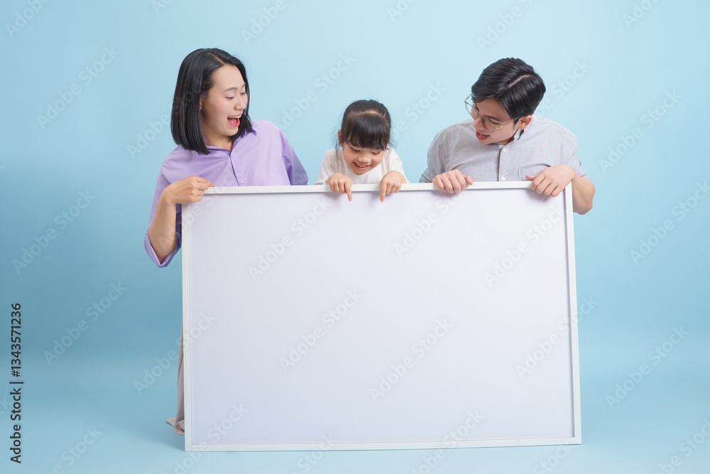 Happy family of three showcasing a blank canvas for creativity in a light blue studio during a fun indoor activity Happy family of three showcasing a blank canvas for creativity in a light blue studio during a fun indoor activity