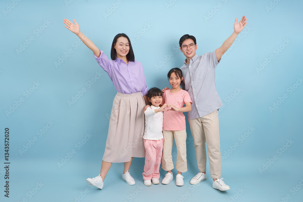 Joyful family posing with cheerful expressions against a light blue background during a casual family photoshoot Joyful family posing with cheerful expressions against a light blue background during a casual family photoshoot