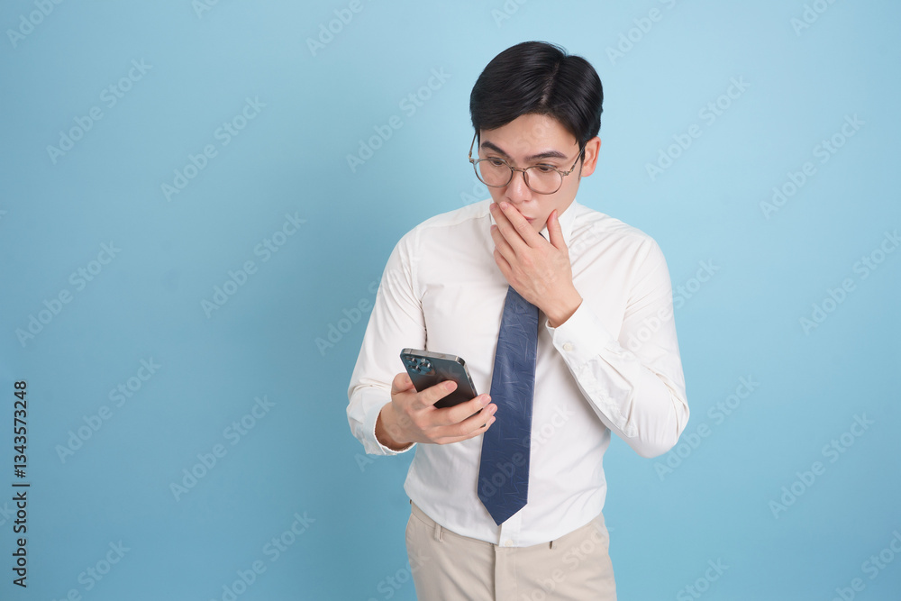 Individual in a formal shirt and tie checking phone with a surprised expression against a light blue background Individual in a formal shirt and tie checking phone with a surprised expression against a light blue background