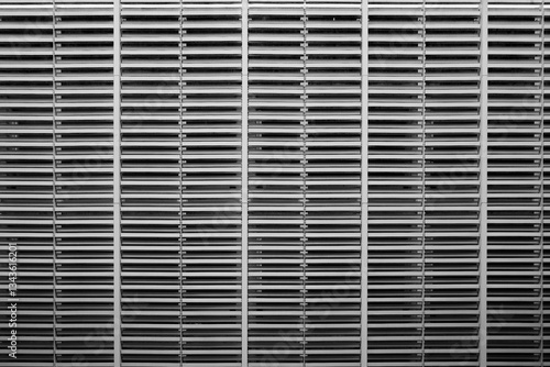 Obraz na plátně A black and white image showcasing a tightly cropped, symmetrical view of a large metal vent or louver system