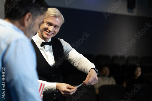 Cuadro en lienzo Smiling usher checking tickets at movie theater entrance