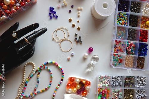 Obraz na płótnie Hand figurine, colorful friendship bracelets, necklaces, various beads and DIY supplies on the table. Making jewelry at home. Flat lay. w salonie