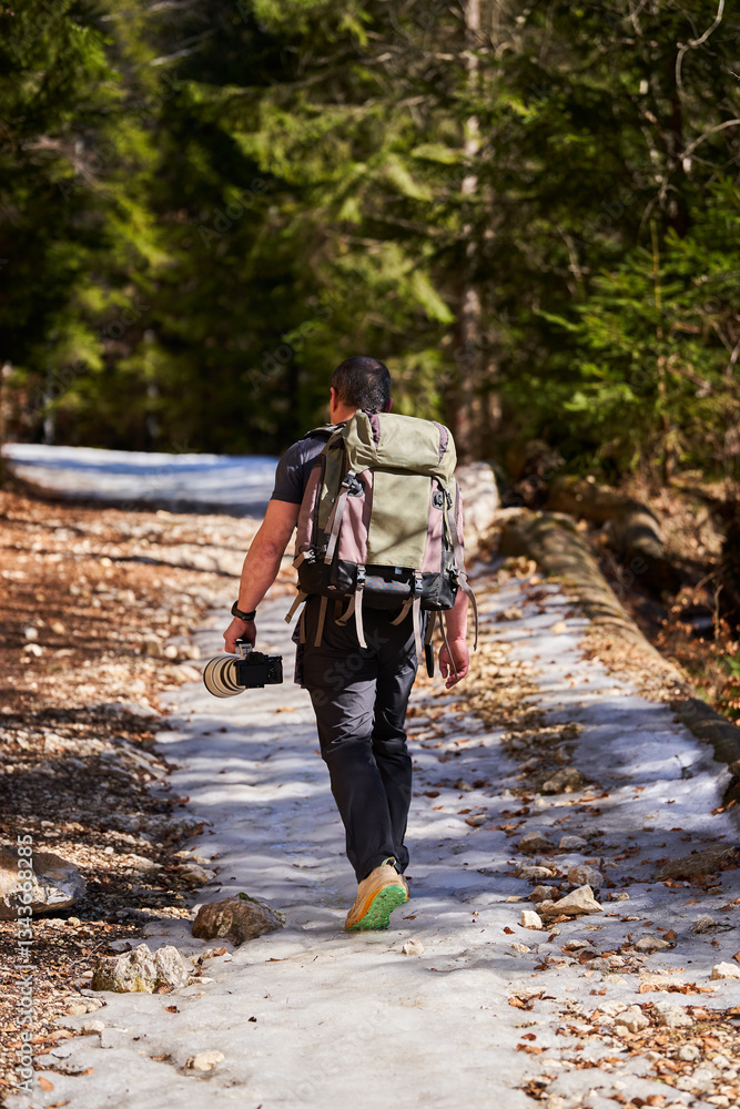 Naklejka premium Photographer hiking through snowy forest........