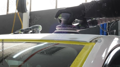 Car body sanding: Close-up of gloved hand using an orbital sander to smooth a car surface, focusing on auto repair and bodywork processes