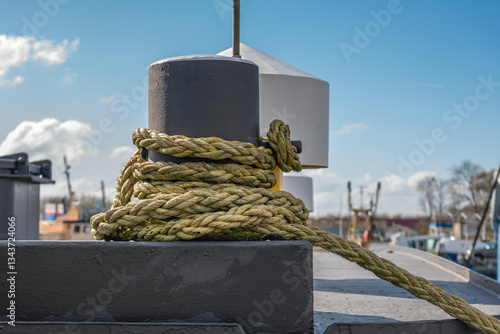 Obraz na płótnie Closeup of a thick rope around a bollard on the deck of a cargo ship moored in the harbor. w salonie