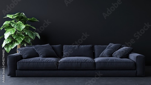 A modern dark sofa against a black wall, complemented by a green potted plant.