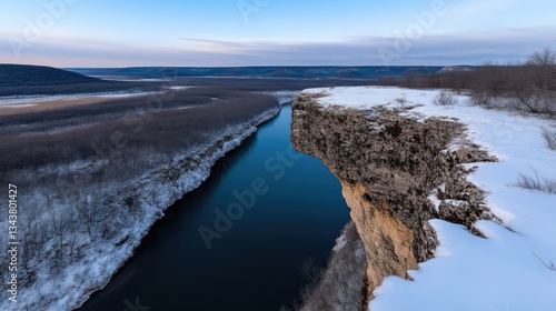 Winter landscape overlooking a river valley from a snowy cliff