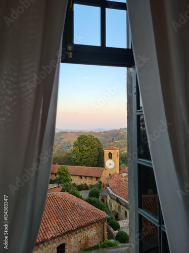 Foto The charming countryside village of Bardassano emerges at sunset, framed by a window's soft curtains