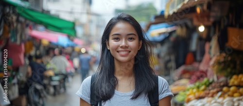 Smiling young woman poses in front of a busy outdoor market