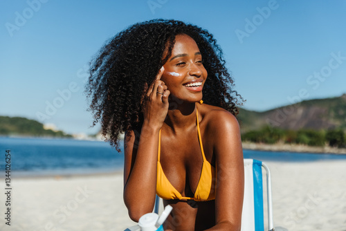 Schilderij op canvas Smiling woman applying SPF sunscreen for protection on a summer day at the beach