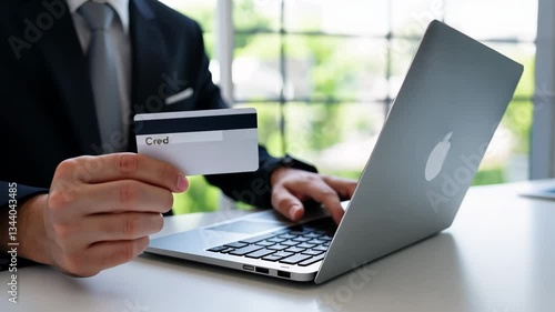Man Holding Credit Card While Using Laptop for Online Shopping