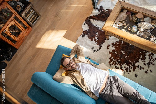 Tableau sur toile Man relaxing on sofa in modern living room with cowhide rug