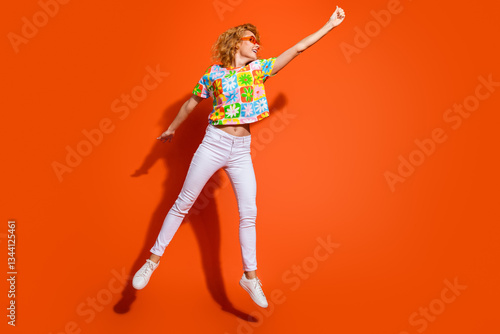 Stylish Young Woman Joyfully Posing in Vibrant Summer Outfit Against Bold Orange Background, Embracing Fun and Fashion Inspiration photo