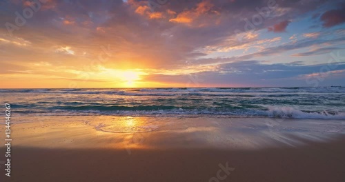 Golden summer sunset over the ocean waves crashing on the sea shore and sand of a tranquil tropical beach
