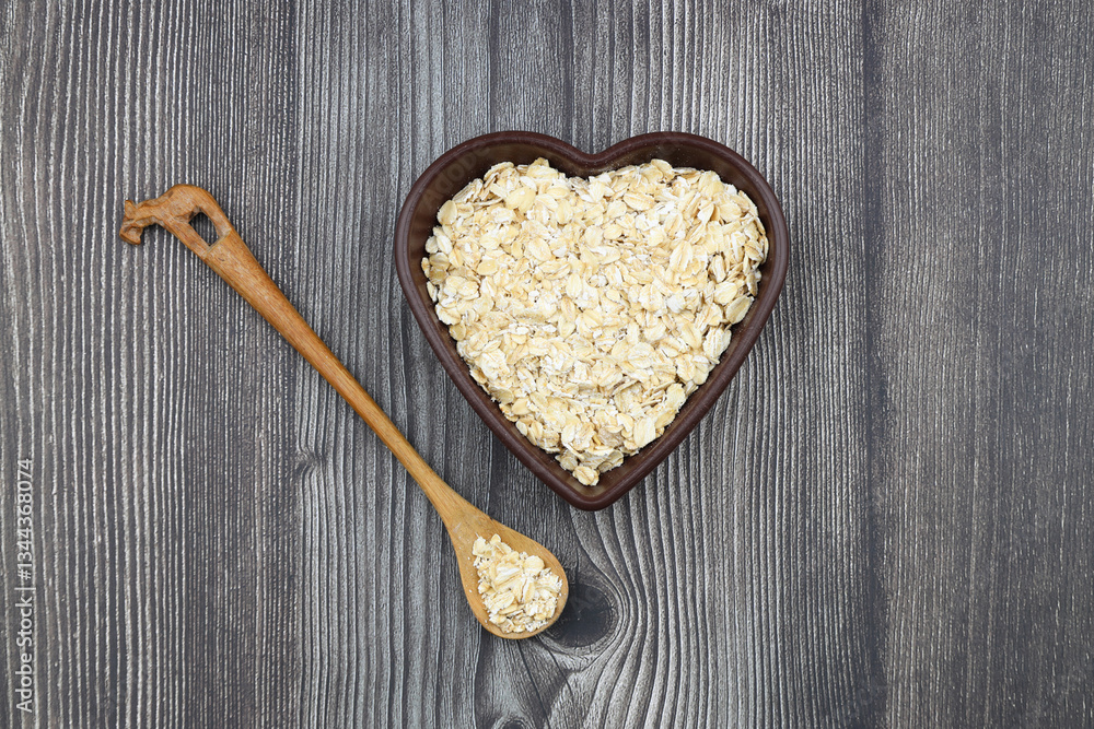 Oatmeal flakes and oats on a heart shaped plate on black background. Healthy breakfast. Organic and vegetarian food. Oatmeal flakes and oats on a heart shaped plate on black background. Healthy breakfast. Organic and vegetarian food.