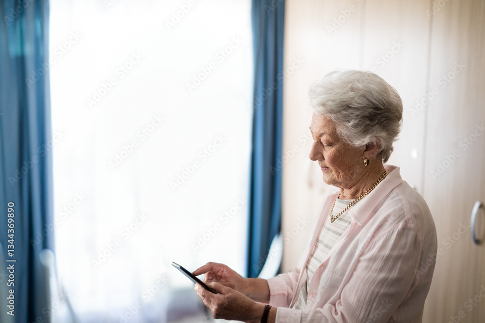 Elderly woman using smartphone at home, staying connected with family, copy space