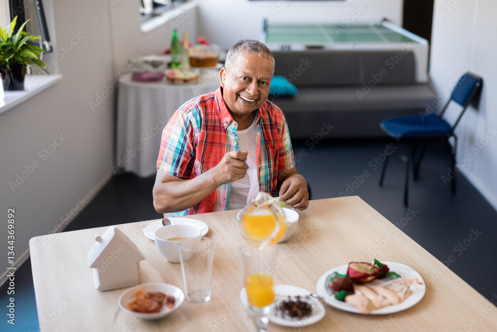 Smiling senior man enjoying breakfast at retirement home dining area Smiling senior man enjoying breakfast at retirement home dining area