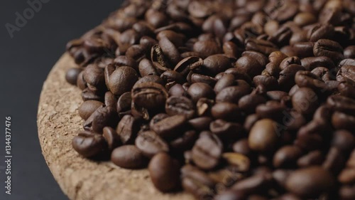 In the shot, black coffee beans on a wooden plate, rotating slowly