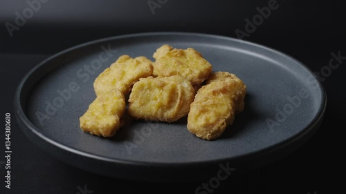 A gray plate is rotating in the frame, chicken nuggets are on the plate. 