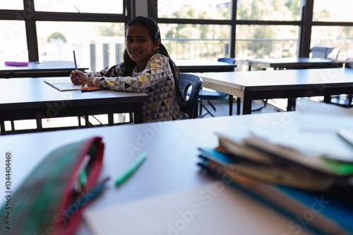 In school  young girl writing in notebook at desk  smiling and focused  copy space