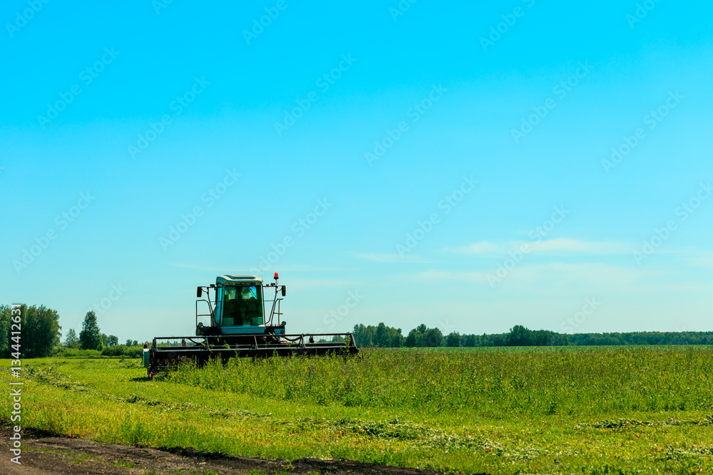 A green tractor is in a field of grass A green tractor is in a field of grass