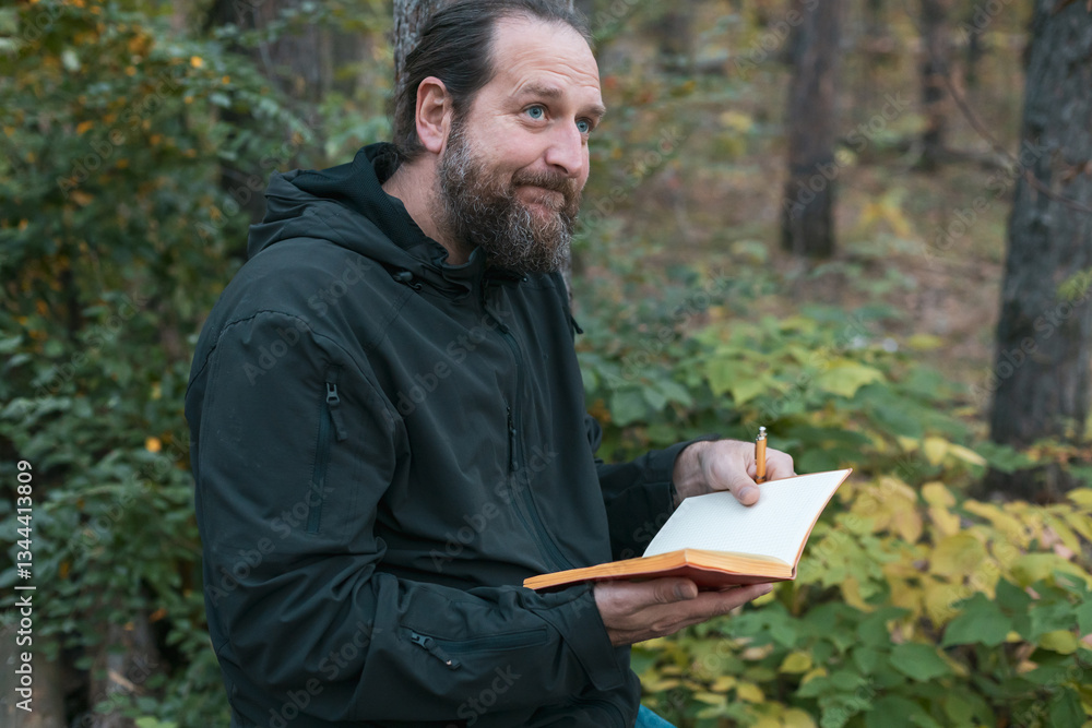 A bearded man in the forest keeps an entry in the red Book A bearded man in the forest keeps an entry in the red Book