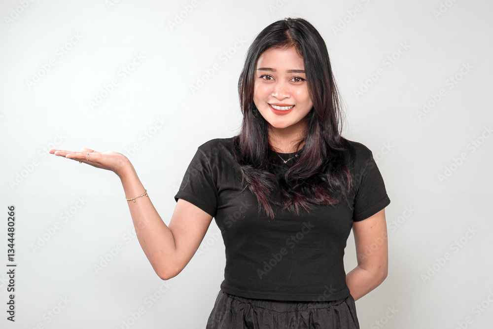 An Indonesian woman in a black outfit smiles warmly while presenting something with one hand. She looks friendly and confident, expressing positivity, invitation, and curiosity. An Indonesian woman in a black outfit smiles warmly while presenting something with one hand. She looks friendly and confident, expressing positivity, invitation, and curiosity.