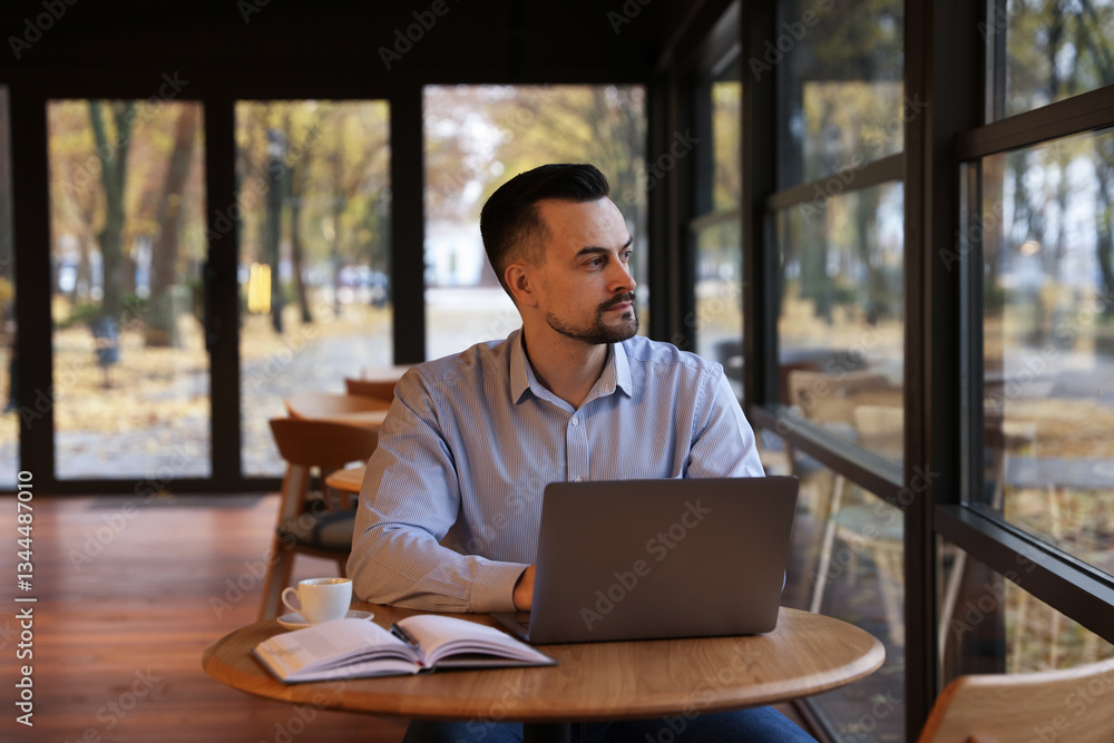 Man working on laptop at table in cafe Man working on laptop at table in cafe