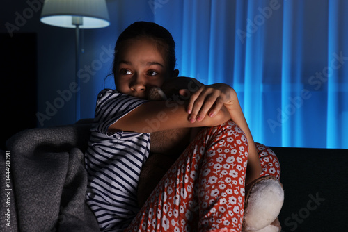 Tableau sur toile Afraid girl with teddy bear on sofa at home