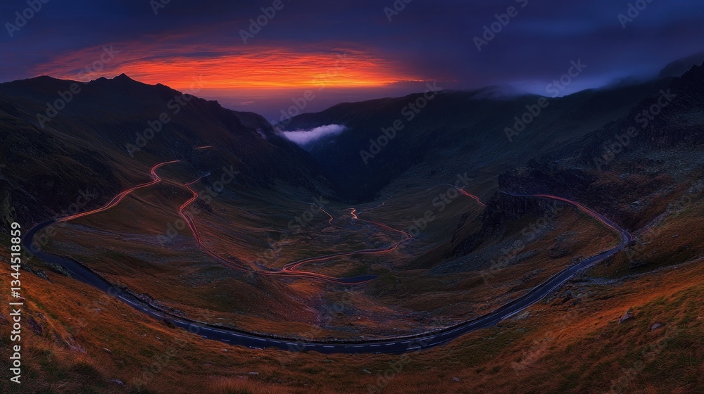 Fototapeta premium Dramatic sunset over winding mountain road in valley.