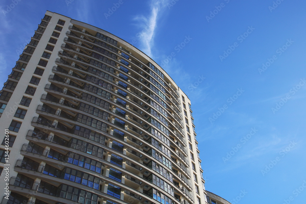 While gazing upwards at a tall building against a blue sky backdrop