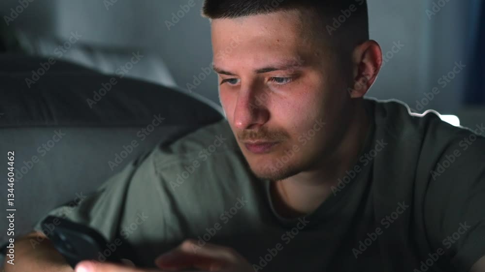 A man with a phone in his hands in a dark room lies on a bed.
A man in a bedroom lies on a bed with a mobile phone in his hands and clicks on the screen A man with a phone in his hands in a dark room lies on a bed.
A man in a bedroom lies on a bed with a mobile phone in his hands and clicks on the screen