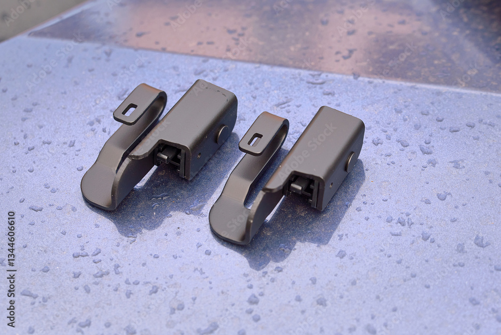 Wiper blade adapter, offset hook mount. Offset hook adapter on wet metallic surface. Wiper blade adapter for windshield visibility improvement, sturdy construction for effective rain and dirt removal