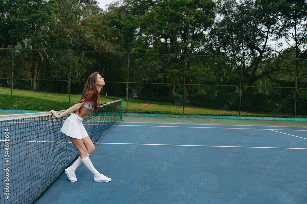 Obraz premium Energetic young woman in white tennis outfit joyful on outdoor court emphasizing healthy lifestyle and sports enthusiasm