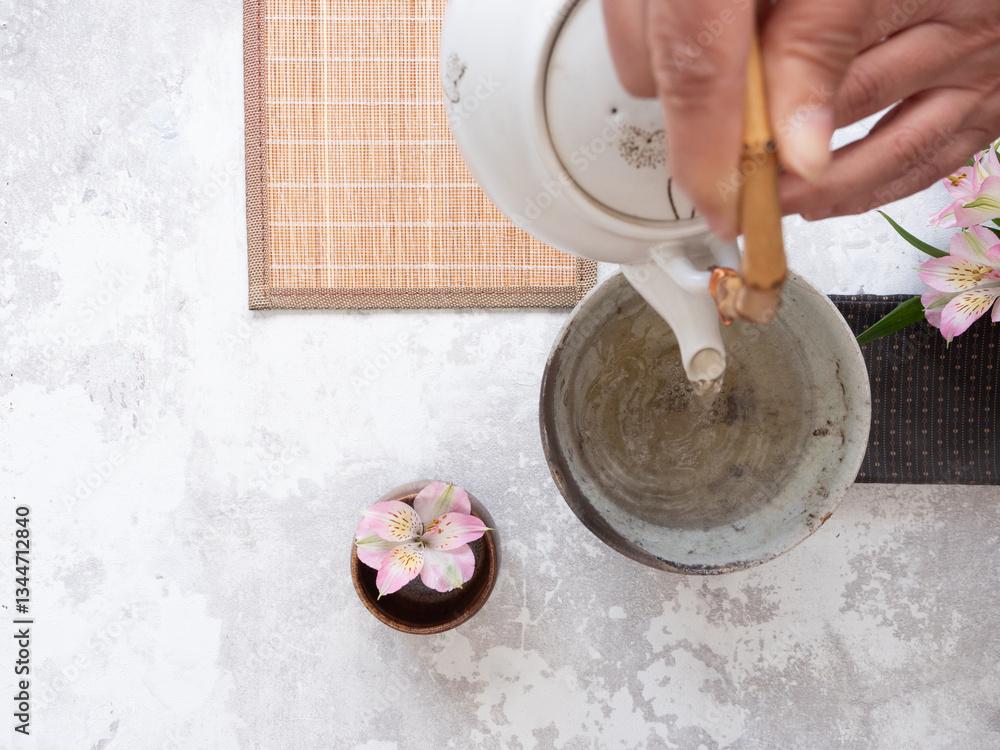 Fototapeta premium Hands pouring tea into a ceramic bowl during a traditional tea ceremony
