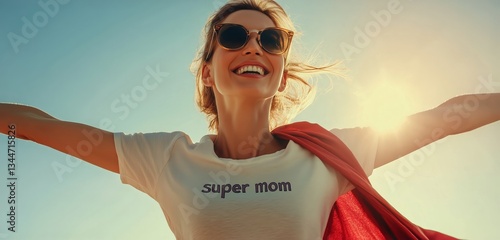 Woman in Red Cape and Sunglasses Celebrates Motherhood Under Bright Blue Sky