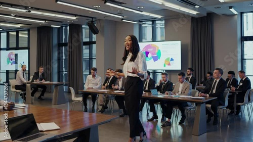 A confident speaker presents key ideas to an attentive audience in a contemporary office setting. Professionals participate and take notes during the engaging session