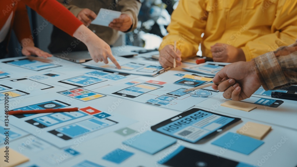 A collaborative workspace shows a diverse team engaged in user interface design. Various devices and notes spread out showcase brainstorming and innovative planning processes. SACTR A collaborative workspace shows a diverse team engaged in user interface design. Various devices and notes spread out showcase brainstorming and innovative planning processes. SACTR