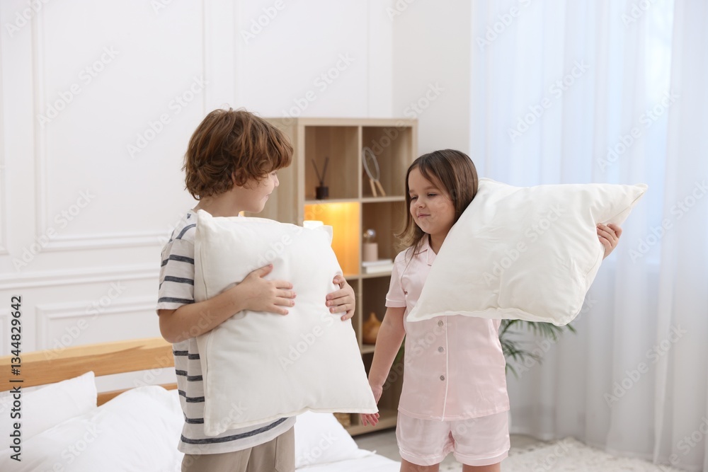 Fototapeta premium Children wearing pajamas having pillow fight in bedroom