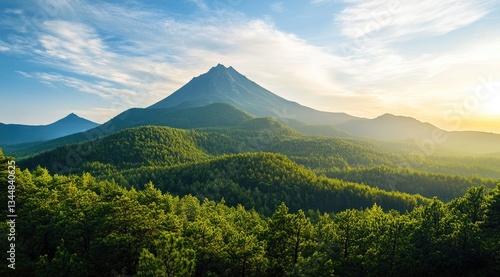 The sun rises in the blue sky, casting its golden rays on green mountains and forests below