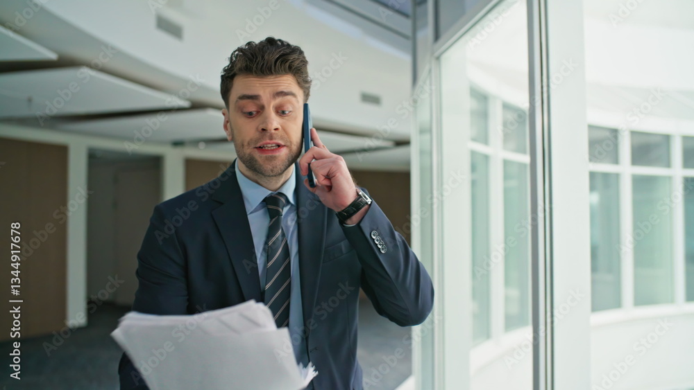 Fototapeta premium Disappointed professional talking smartphone holding documents hallway closeup
