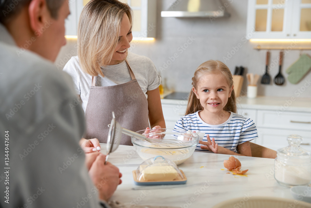 Happy parents and their daughter making dough at white marble table in kitchen Happy parents and their daughter making dough at white marble table in kitchen