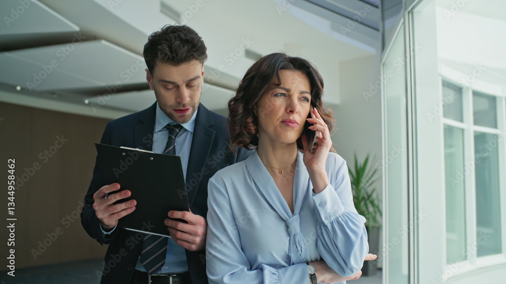Woman ceo talking mobile phone walking office hallway with man secretary closeup Woman ceo talking mobile phone walking office hallway with man secretary closeup