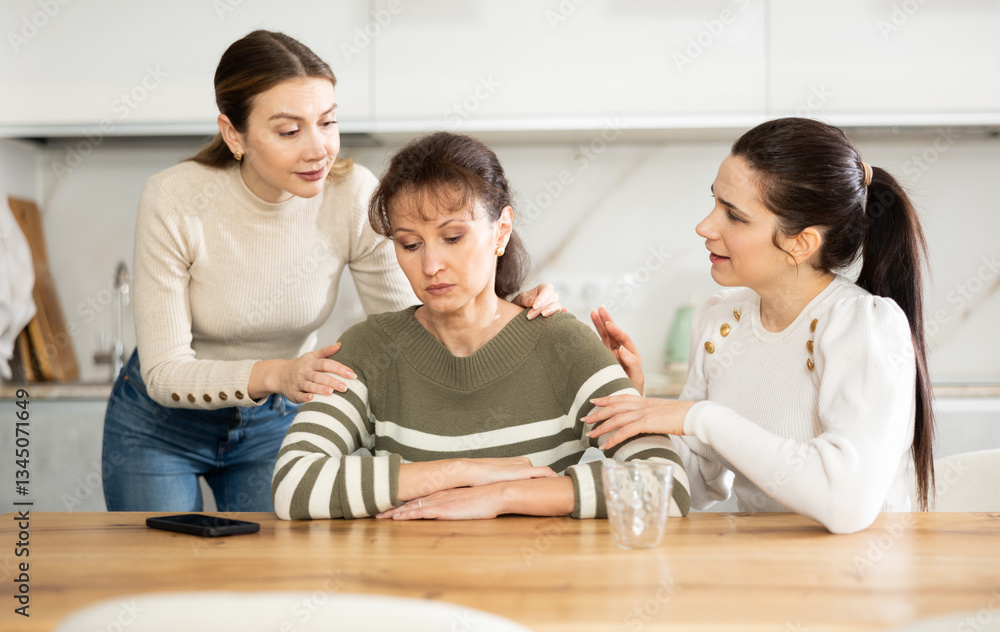 Woman is upset, sitting and grieving at table. Two female friends reassure and encourage her, express support and sympathy Woman is upset, sitting and grieving at table. Two female friends reassure and encourage her, express support and sympathy