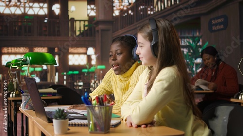 Girls participating in online course at the library joining live video webinar with their teacher to complete a school project. Scholars working on an assignment via video call lesson. Camera A.