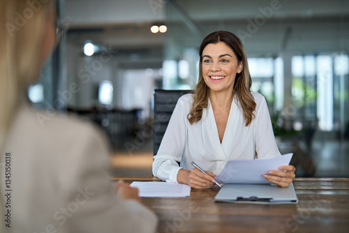 Foto Happy mature professional business woman executive hr manager having job interview or business discussion with female applicant or colleague sitting at workplace in corporate office meeting