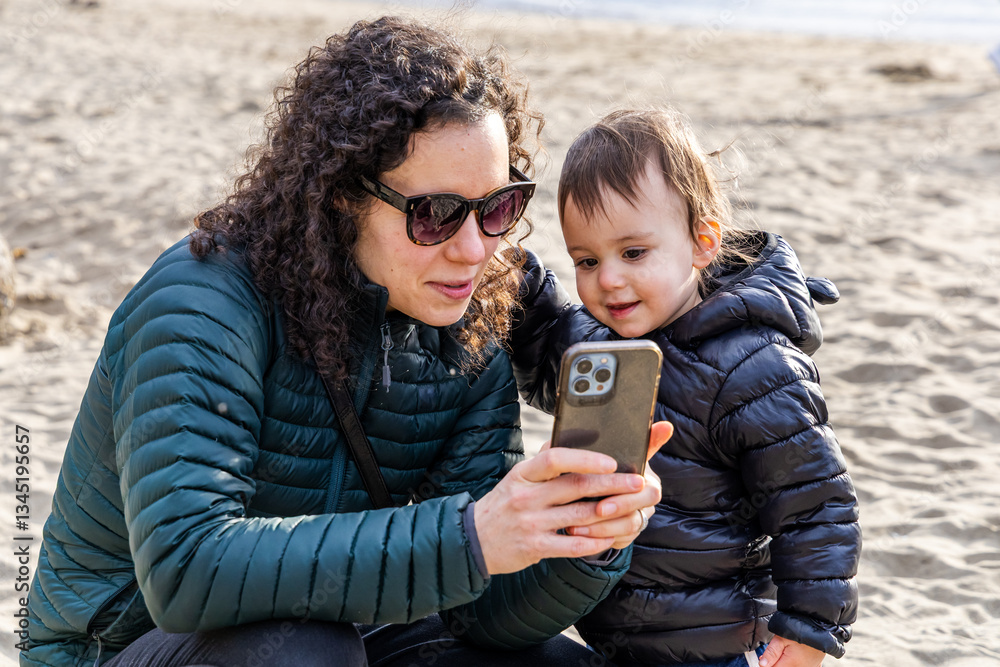 Fototapeta premium Mother and Child Enjoying Quality Time Viewing Phone at Stanley Park Beach
