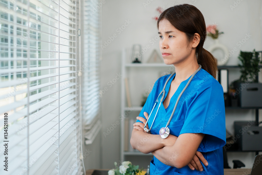 Female nurse in blue scrubs gazes thoughtfully out a window in a medical office, conveying a sense of contemplation and dedication. Female nurse in blue scrubs gazes thoughtfully out a window in a medical office, conveying a sense of contemplation and dedication.